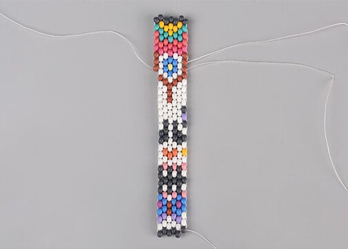 Five columns of seed beads stitched together with an additional quarter-column on the left and right. On the right, seed beads have been added in a column starting from the bottom so that the dangling thread from the quarter column in Step 5 is met by a new dangling thread sewn in Step 6a